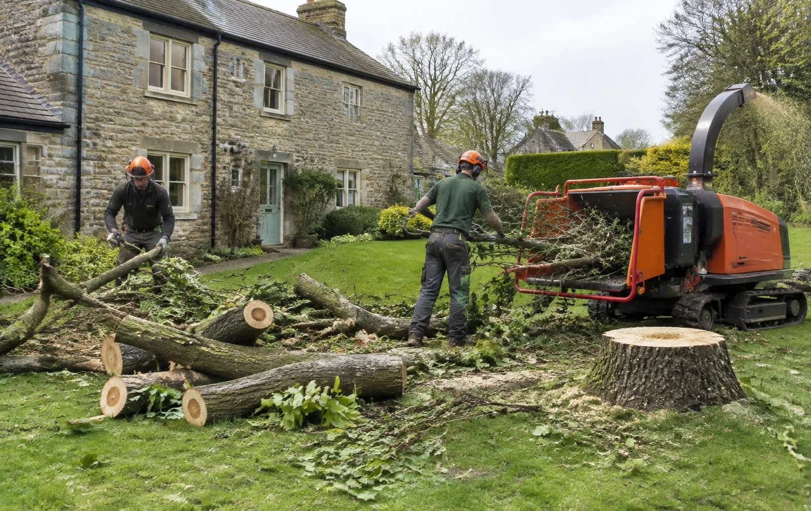 Arborists clearing timber and chipping branches at a stone village house, near Collingham